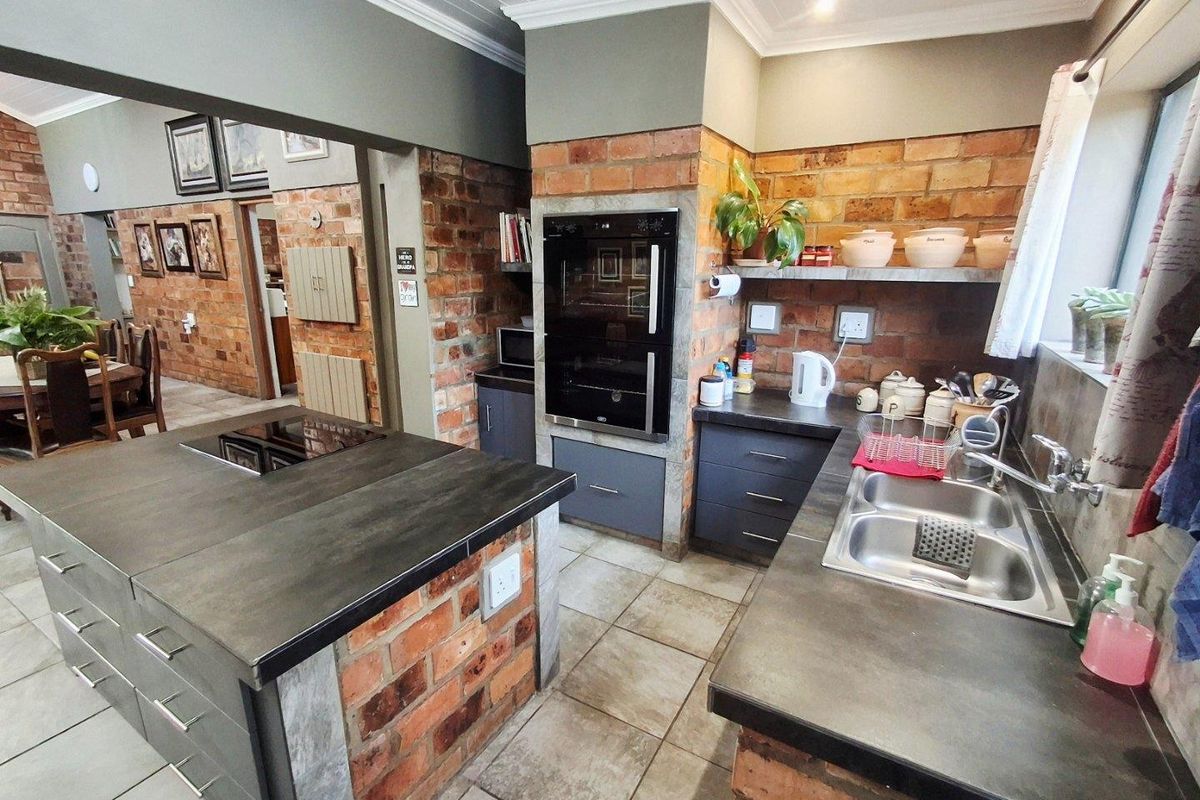 A rustic-style kitchen featuring exposed brickwork, a central island with a built-in hob, and a double-eye-level oven.