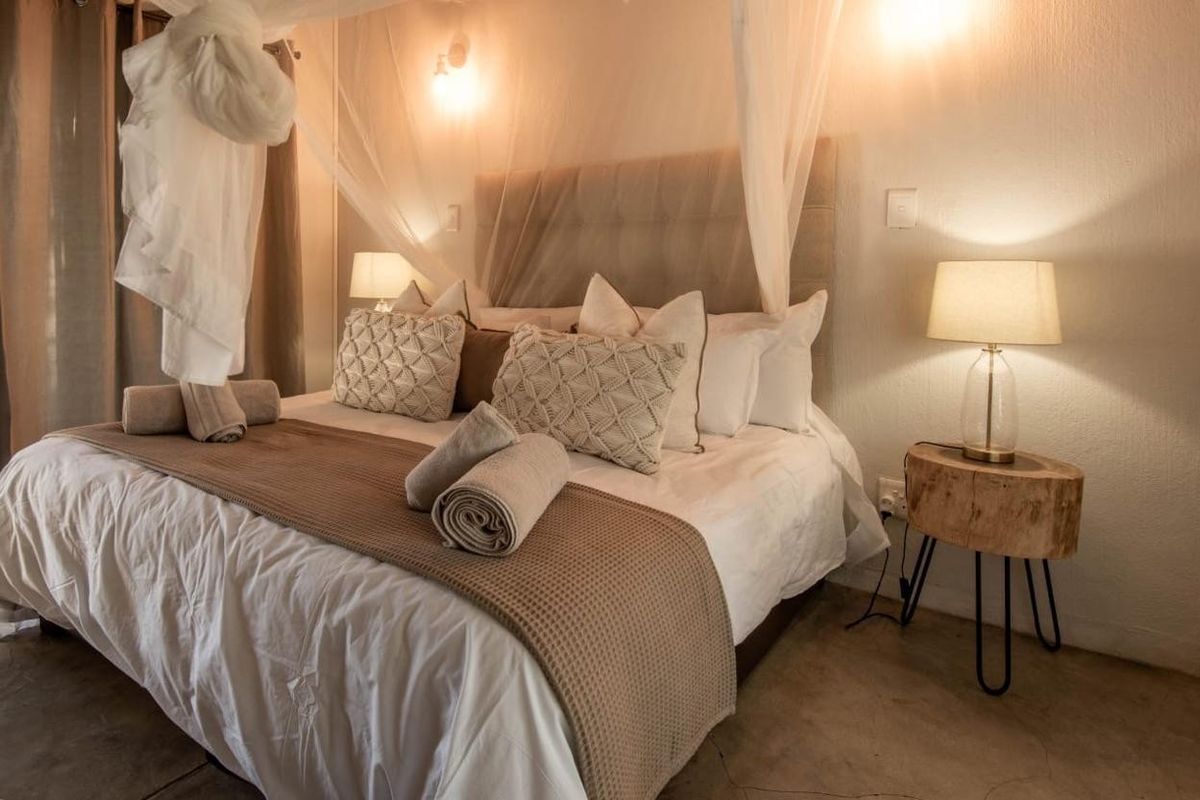 A cozy bedroom featuring a neutral color palette, polished concrete flooring, and warm ambient lighting.
