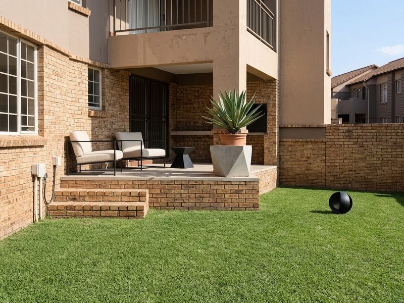 A well-maintained rear exterior featuring a paved patio with a built-in braai, brick facade, and access to a private garden area.