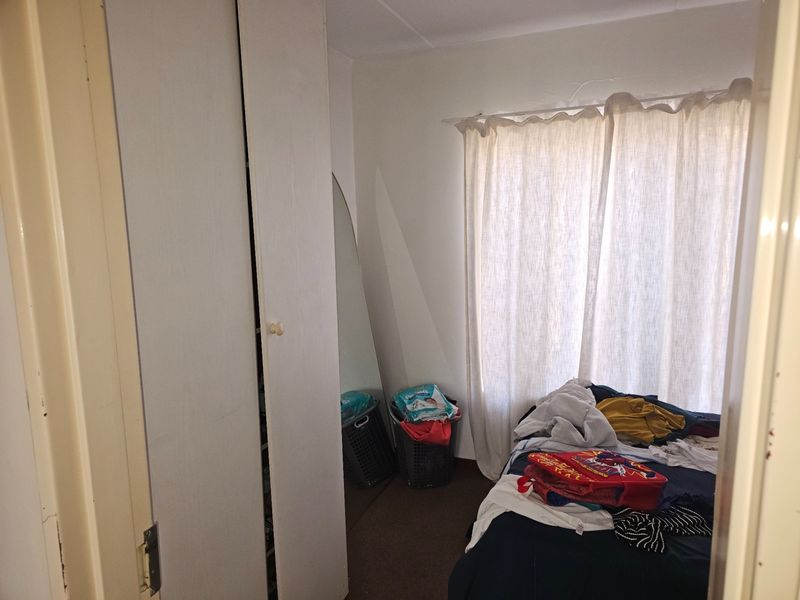 A bedroom featuring a built-in wardrobe and a window with a curtain rail, requiring some cosmetic updates to improve its overall appeal.