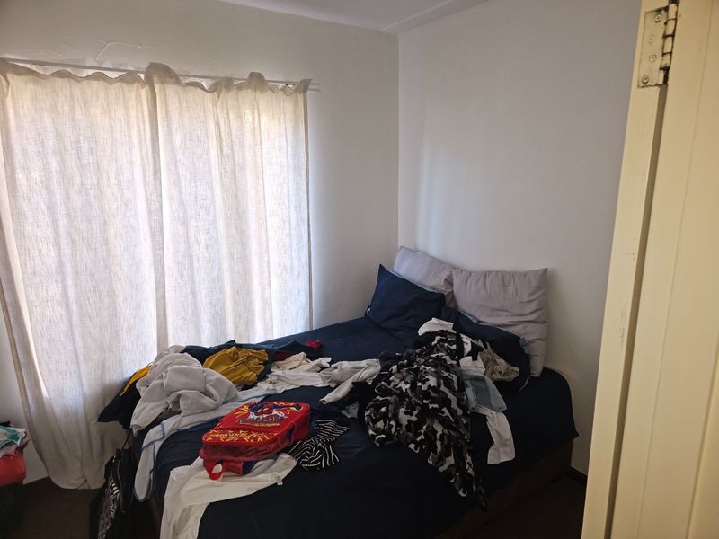 A standard bedroom featuring neutral walls and a window with a curtain rod, providing a functional space for rest.