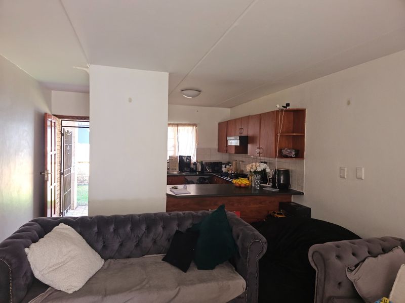 Open plan living area featuring a functional kitchen with built-in cabinetry, breakfast bar, and direct access to an outdoor space.
