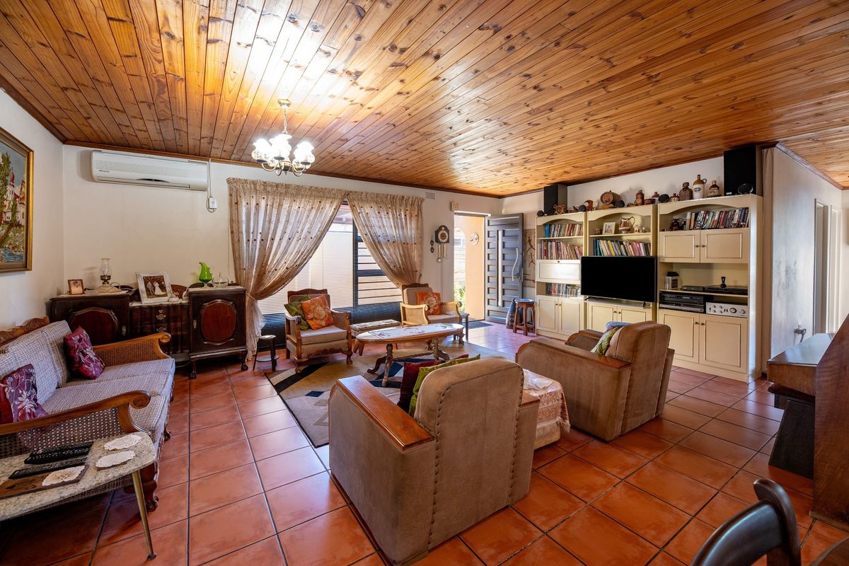 Spacious living room featuring a distinctive timber-clad ceiling, terracotta floor tiles, and a large built-in wall unit with integrated shelving.