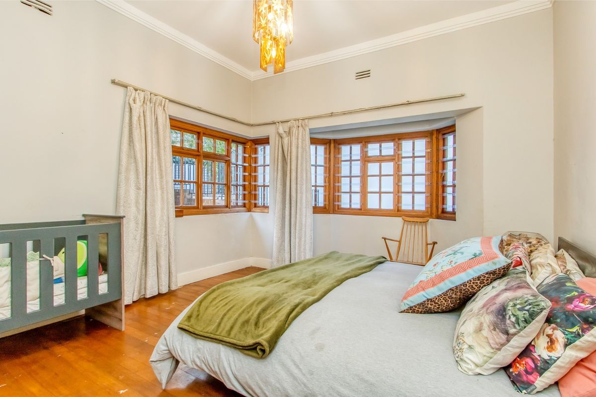 A bedroom featuring timber-framed bay windows, polished wooden flooring, and decorative ceiling lighting.