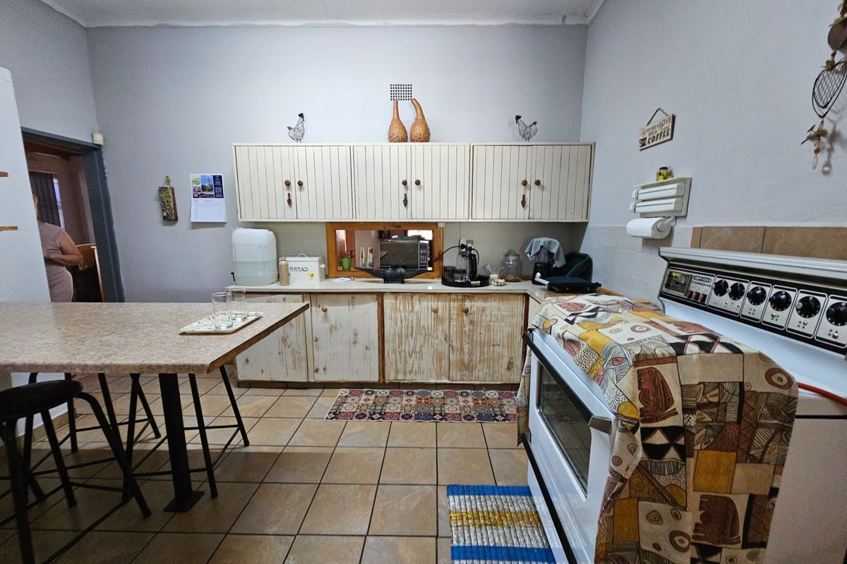 A functional kitchen featuring wooden cabinetry, tiled flooring, and a built-in stove, offering a practical layout for daily meal preparation.