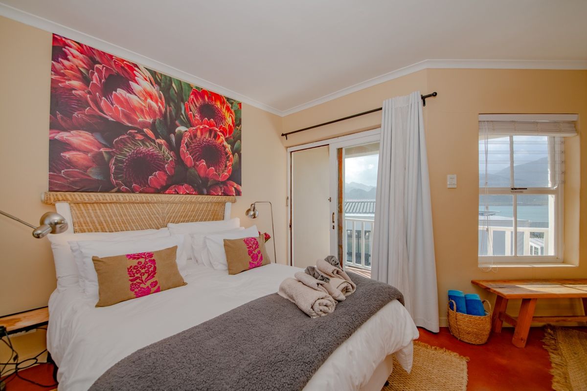 A well-lit bedroom featuring a sliding door leading to a balcony with scenic views, neutral wall tones, and a large window.