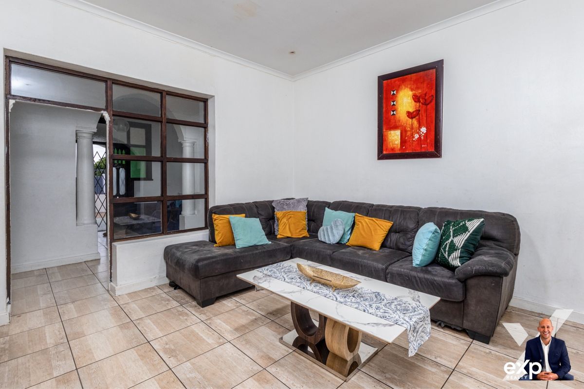 A living room featuring tiled flooring and a distinctive internal timber-framed glass partition wall, providing a view into the adjacent space.