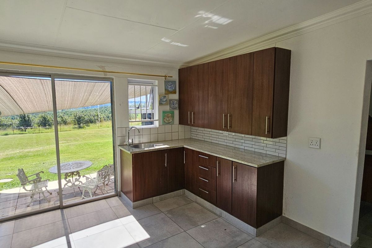 Compact kitchen featuring dark wood cabinetry, stone countertops, and direct access to the outdoor patio through a sliding glass door.