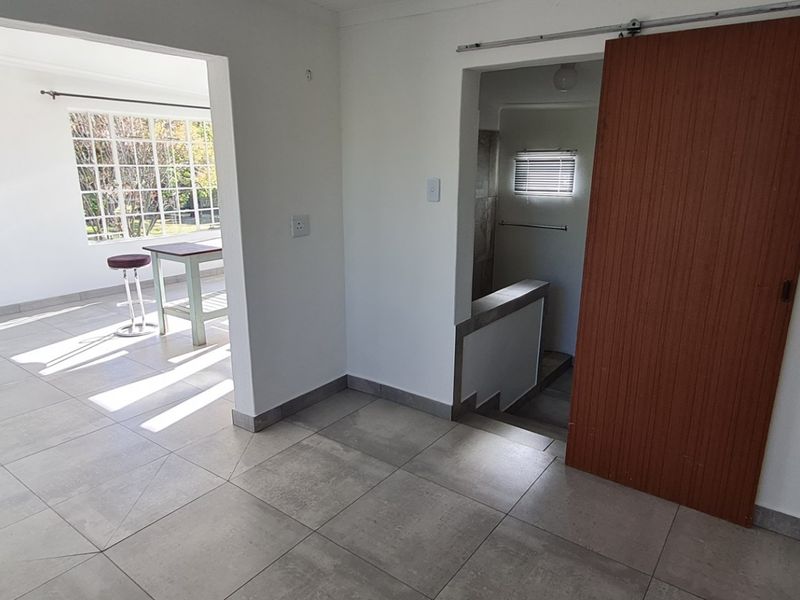 An open-plan living area featuring neutral tiled flooring, a sliding barn door, and direct access to an internal staircase.