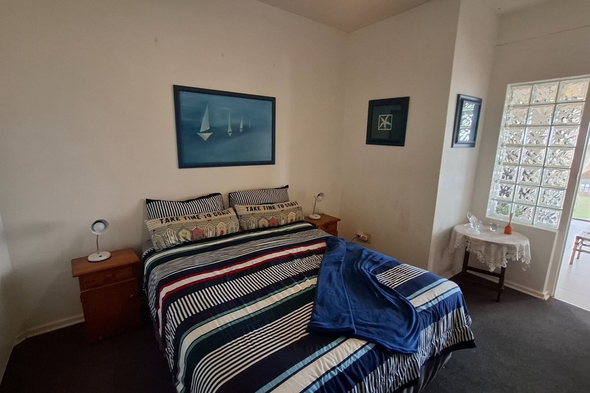 A bedroom featuring dark carpeting and a distinctive glass block window, providing natural light and access to an adjoining patio area.