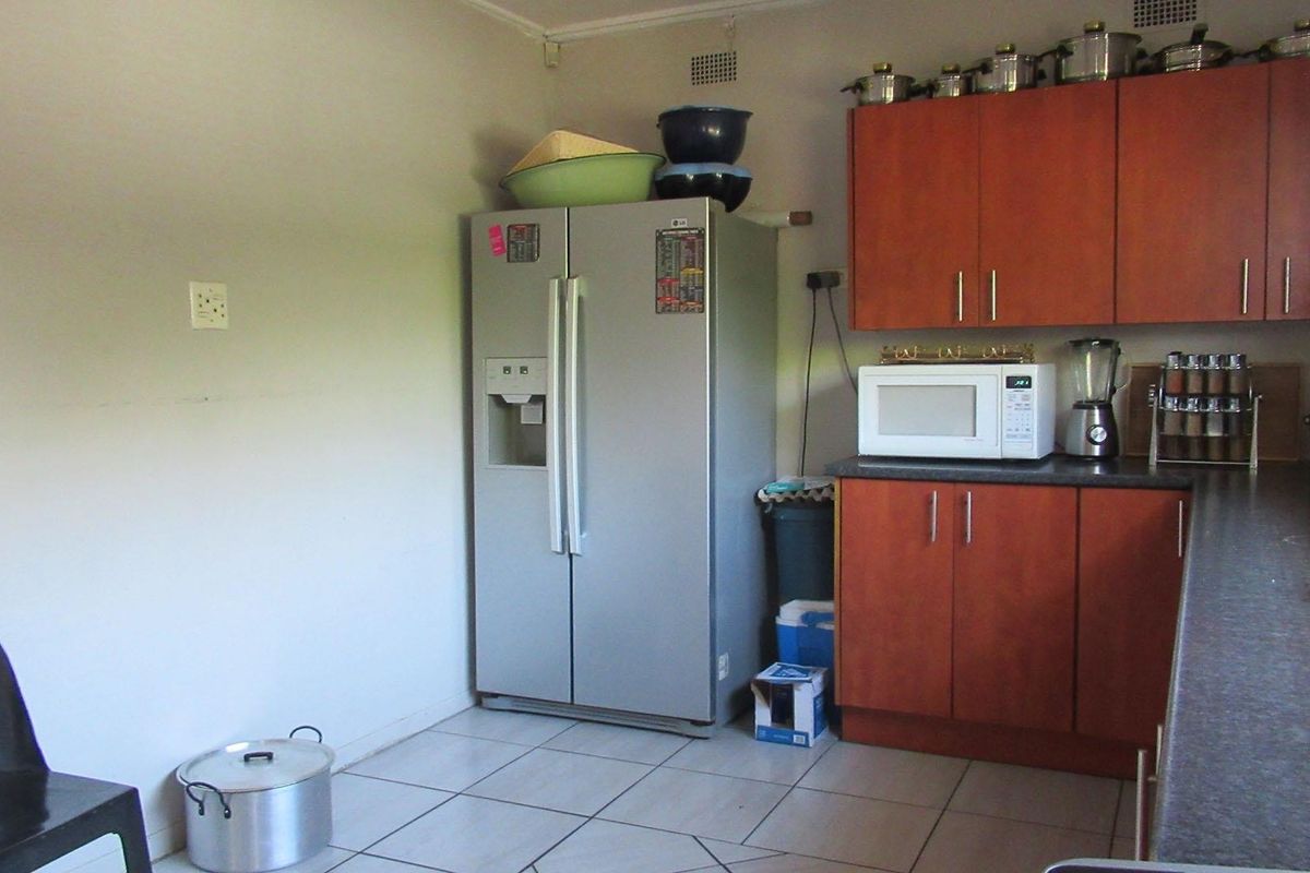 A functional kitchen featuring wood-toned cabinetry, dark laminate countertops, and tiled flooring, providing a practical workspace for daily meal preparation.