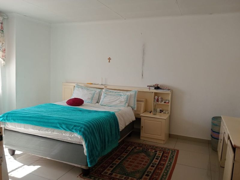 A bedroom featuring tiled flooring and a built-in headboard with integrated bedside storage.