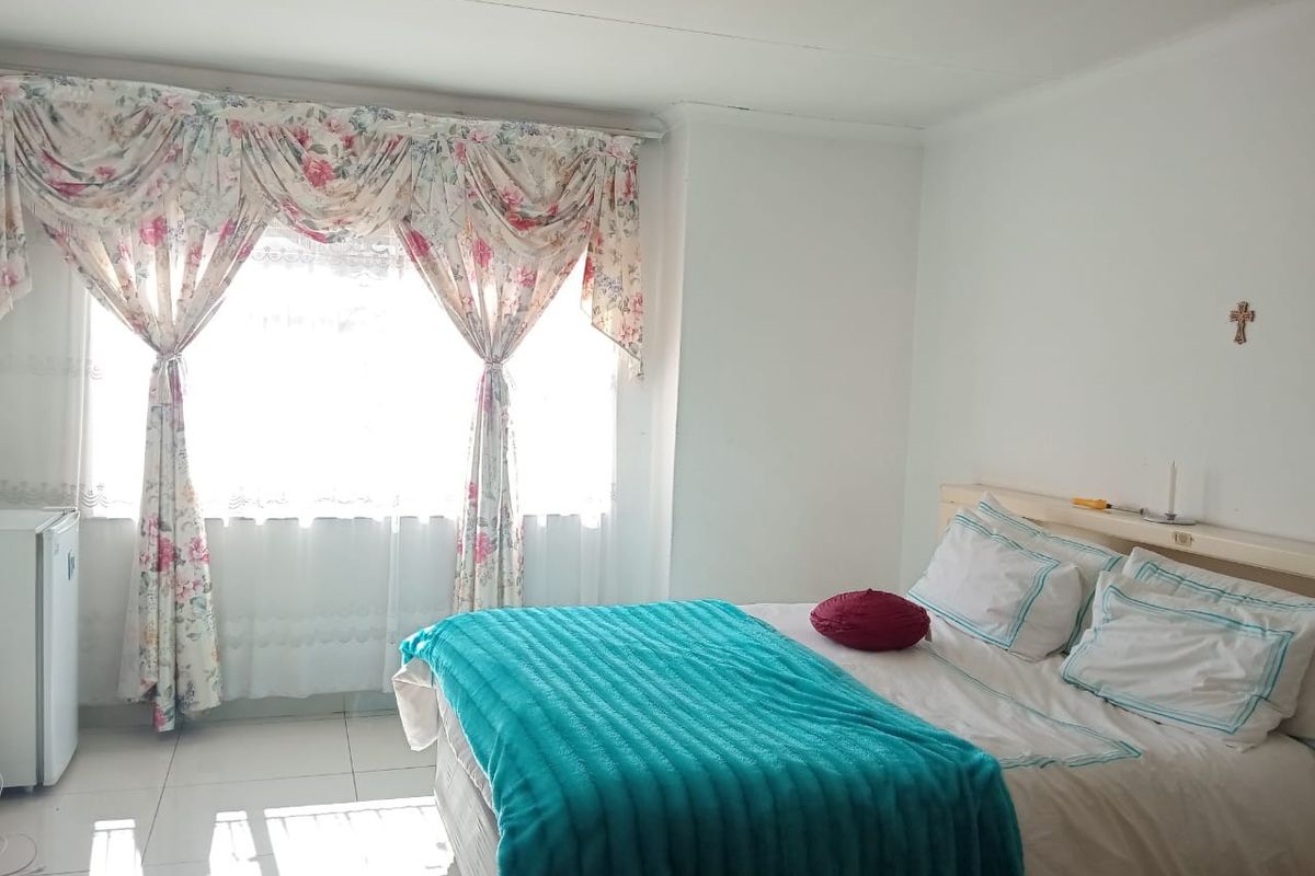 A bedroom featuring tiled flooring and a large window with natural light.