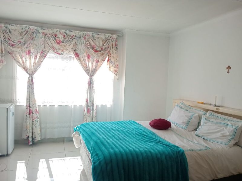 A bedroom featuring tiled flooring and a large window with natural light.
