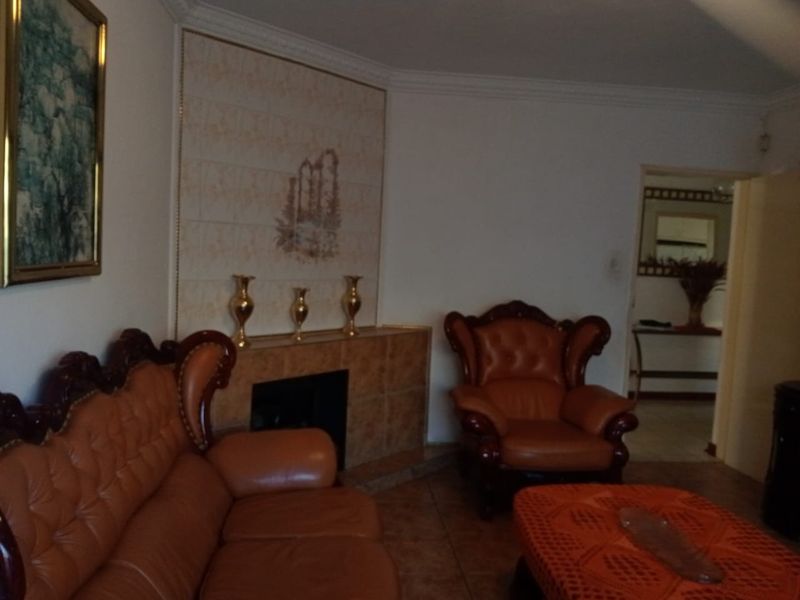 A living room featuring a tiled fireplace surround with decorative wall paneling and crown molding.