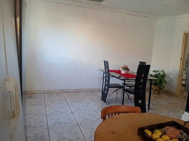 A functional dining area featuring tiled flooring and plain walls, offering a blank canvas for potential interior updates and styling.