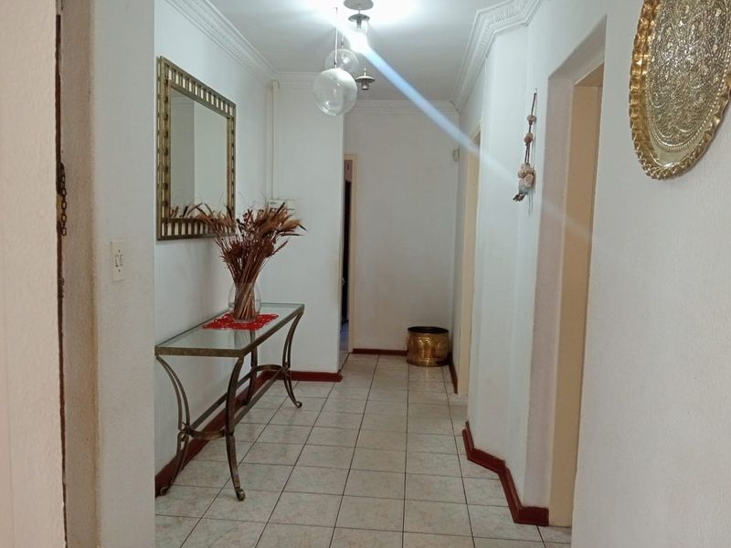 A functional hallway featuring tiled flooring, decorative cornice detailing, and multiple access points to adjoining rooms.