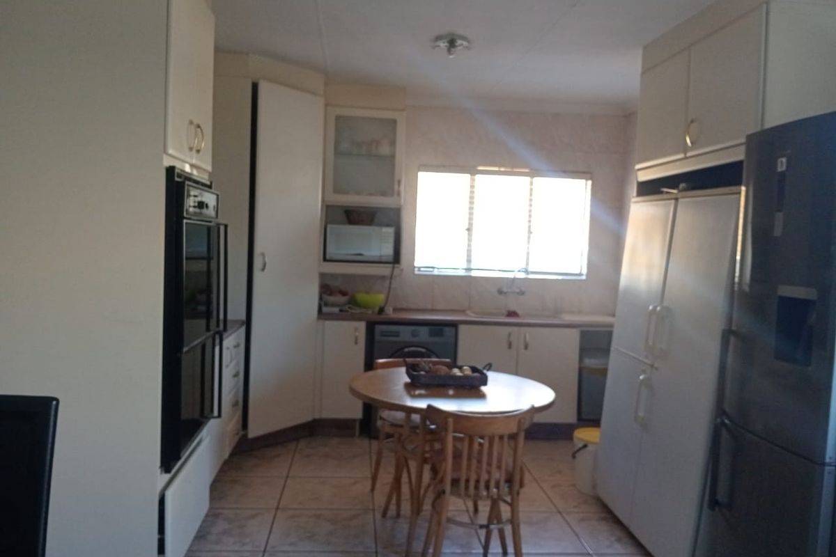 A functional kitchen featuring built-in cabinetry, a wall-mounted oven, tiled flooring, and a window providing natural light.