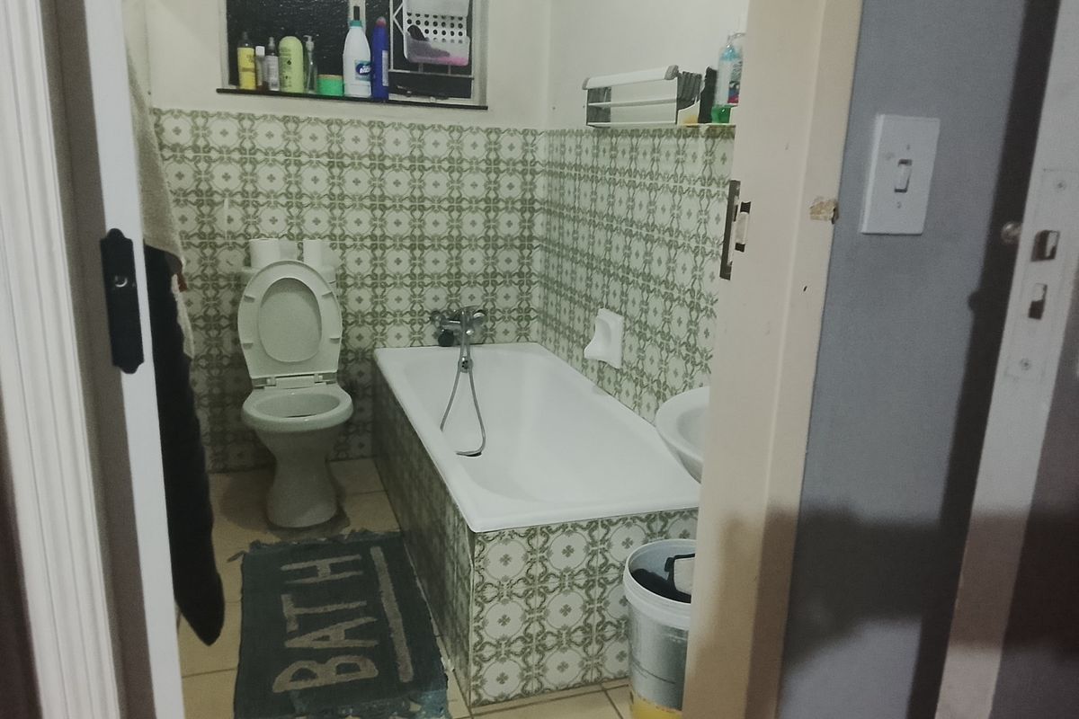 A functional bathroom featuring a bathtub, toilet, and basin with vintage-style patterned wall tiles.