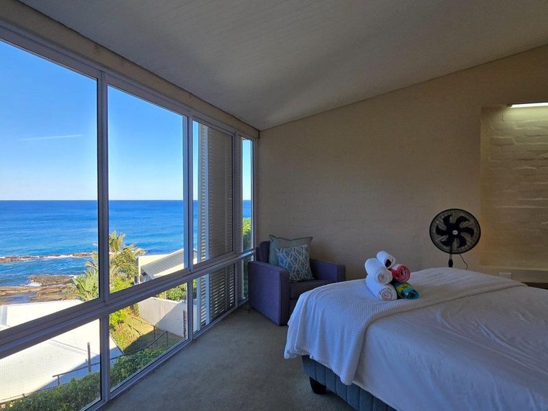 A bedroom featuring expansive floor-to-ceiling windows that offer panoramic ocean views, providing a bright and airy atmosphere.