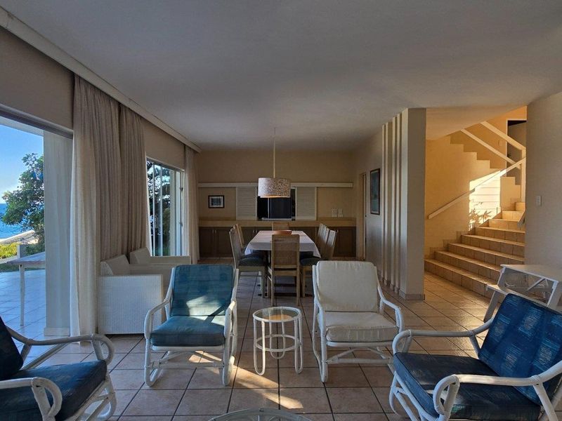 Spacious open-plan living and dining area featuring large sliding glass doors with ocean views and an internal staircase.