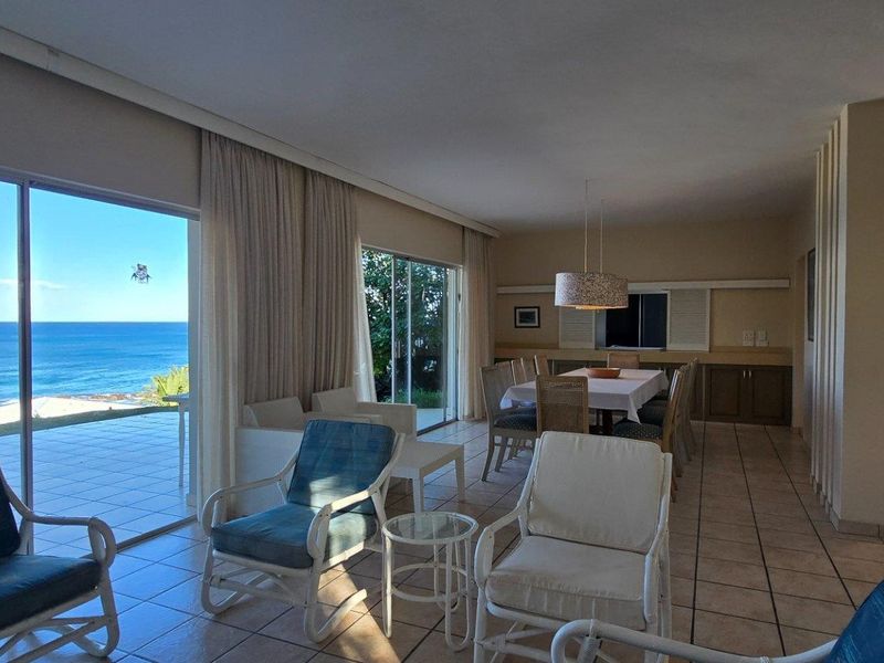 Spacious open-plan living and dining area featuring large sliding glass doors that open to a patio with panoramic ocean views.