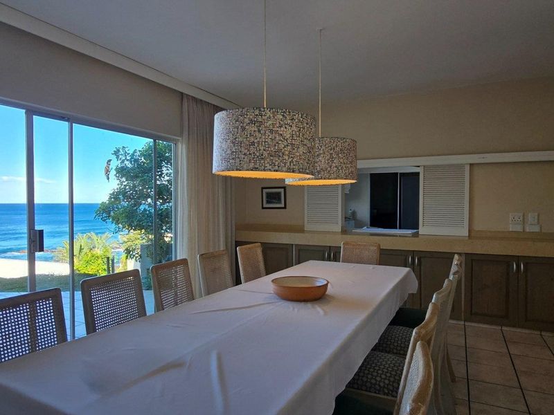 Spacious dining area featuring large sliding glass doors with direct ocean views, built-in cabinetry, and tiled flooring.