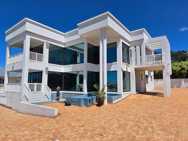 A modern multi-story residential property featuring large glass windows, a paved courtyard, and a swimming pool.
