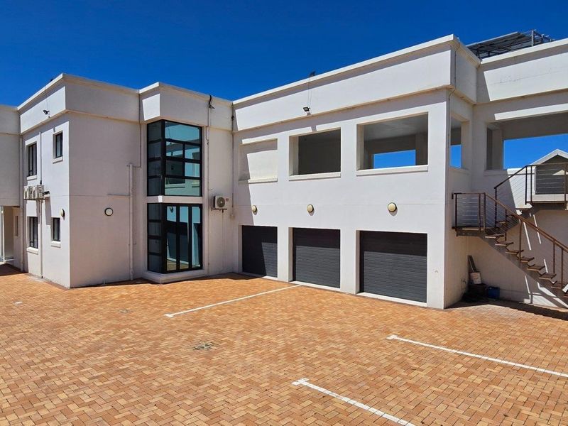 A modern multi-level exterior view featuring a paved driveway, triple garage, external staircase, and balcony areas under a clear blue sky.