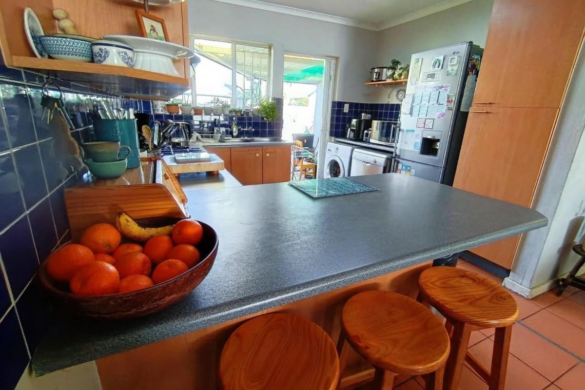 A functional kitchen featuring a breakfast bar, tiled backsplash, and integrated cabinetry with direct access to an outdoor patio area.