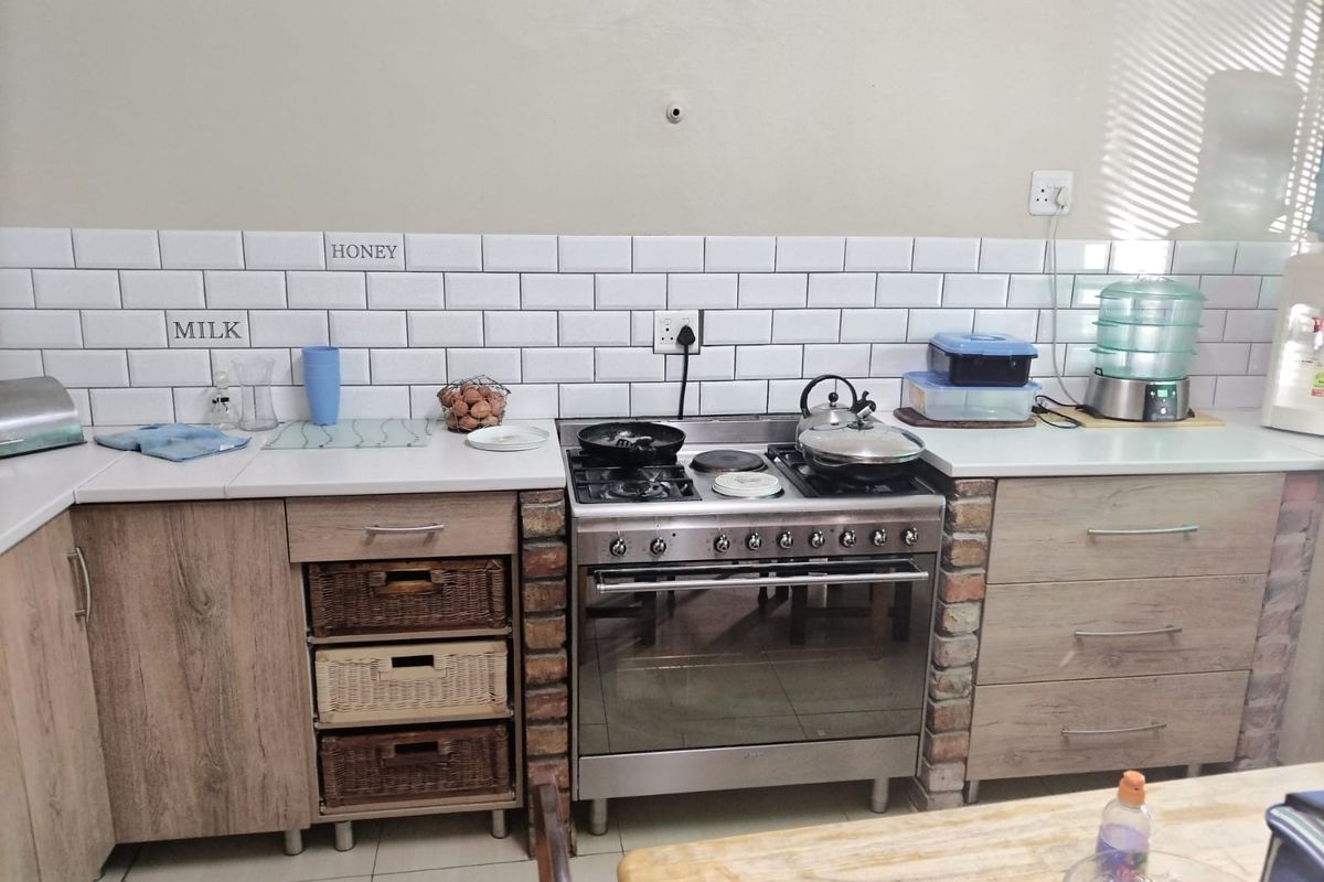 A functional kitchen area featuring wood-look cabinetry, a subway tile backsplash, and a freestanding stainless steel oven with a gas cooktop.