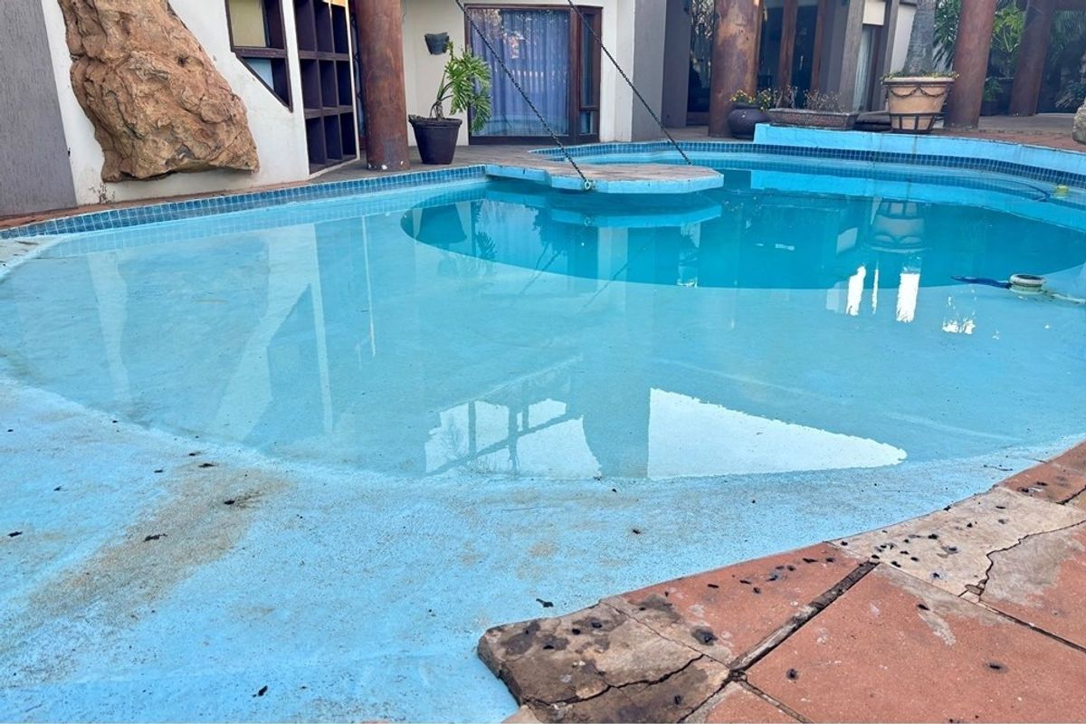 Outdoor swimming pool area featuring a built-in stone element and tiled surround, showing signs of wear and surface deterioration.
