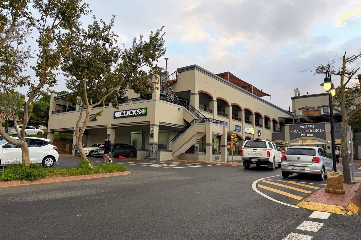 Exterior view of a multi-level commercial office and retail building featuring covered parking, external staircases, and prominent mall entrance signage.