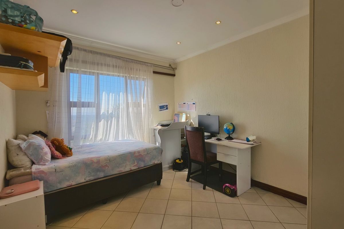A functional bedroom featuring tiled flooring, recessed ceiling lighting, and a large window allowing for natural light.