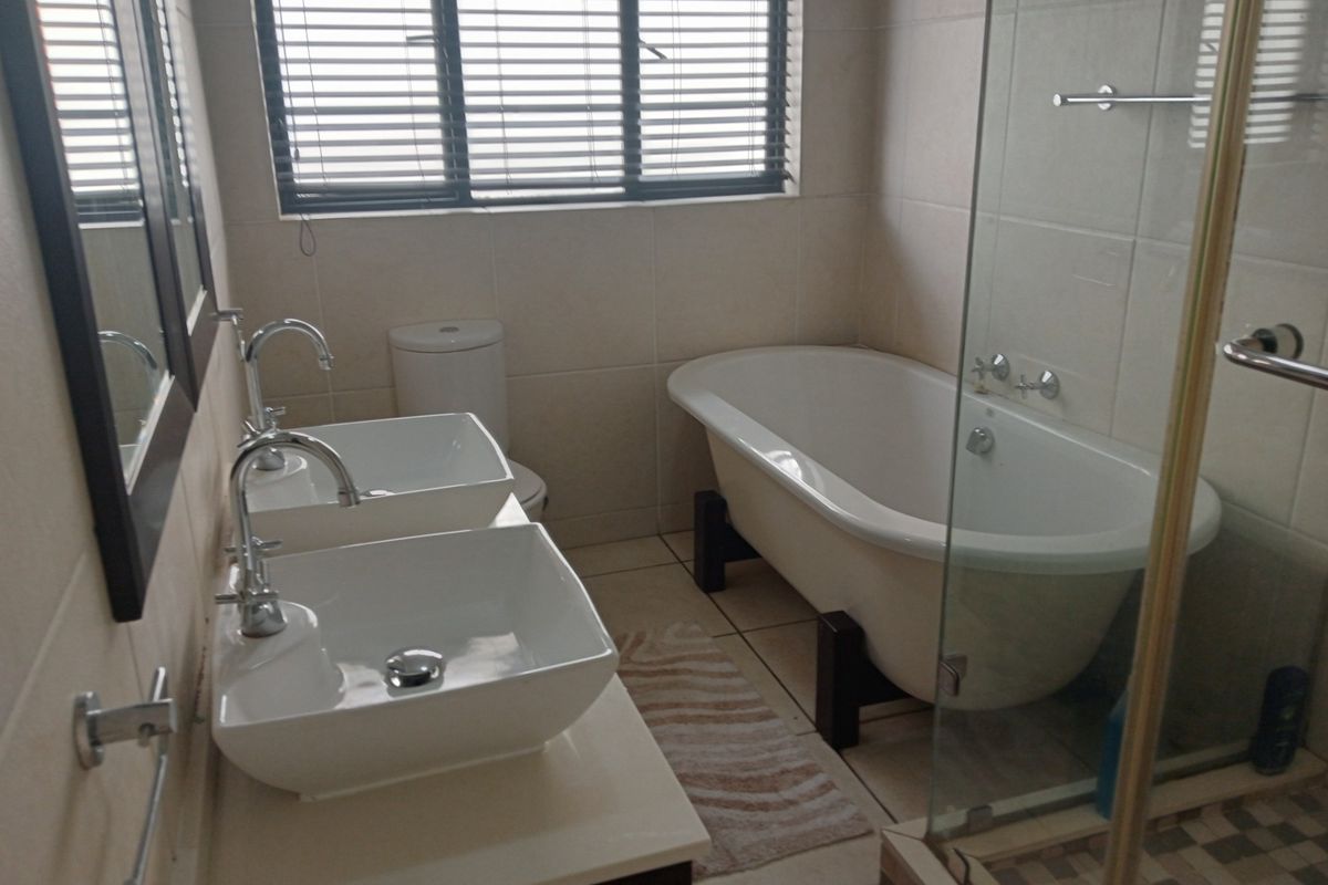 Modern bathroom featuring a double vanity with vessel sinks, a freestanding bathtub, and a separate glass-enclosed shower with tiled flooring.