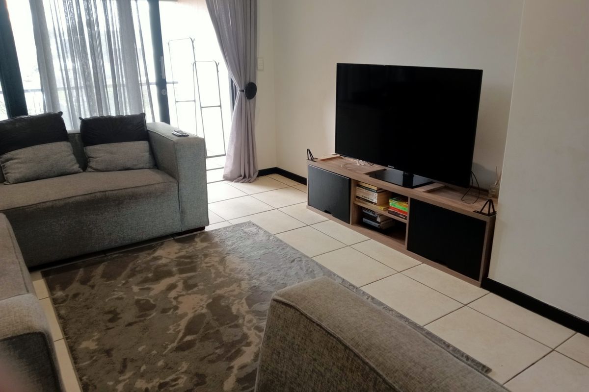 A comfortable living room featuring tiled flooring and large sliding glass doors that provide access to an outdoor balcony area.
