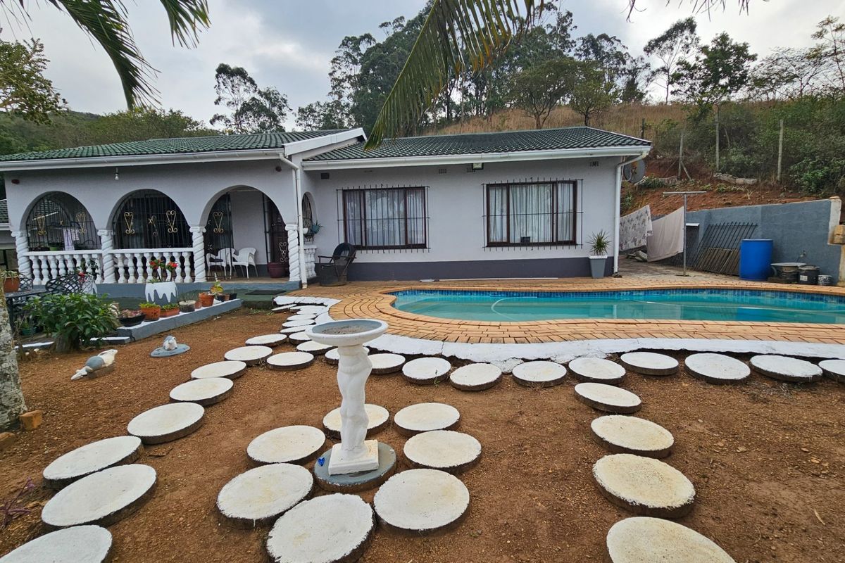 Rear view of the house featuring a swimming pool, covered patio with arched columns, and a landscaped garden area with stepping stones.