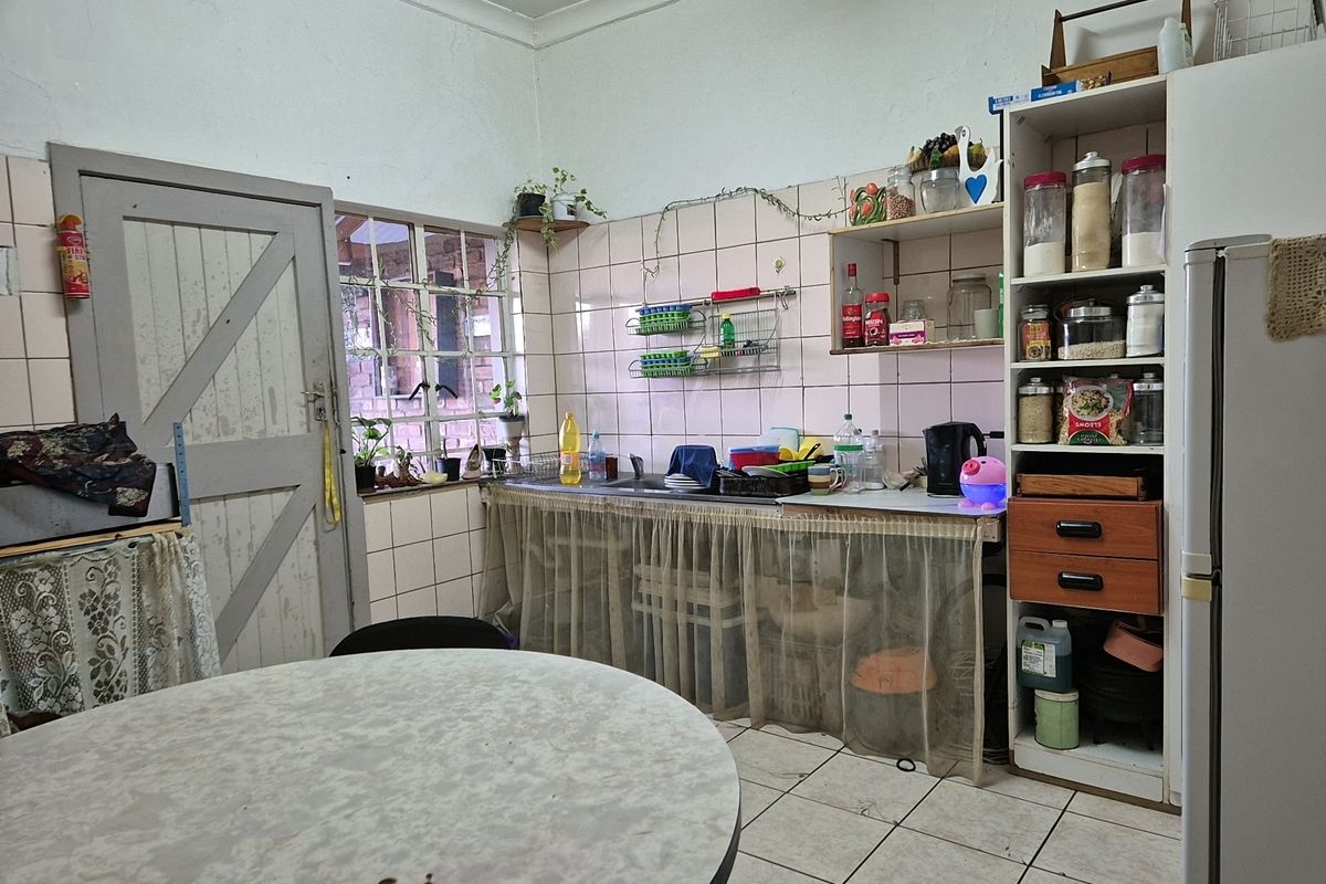 A functional kitchen area featuring tiled walls, a built-in sink, and integrated shelving, offering a practical layout with potential for modernization.