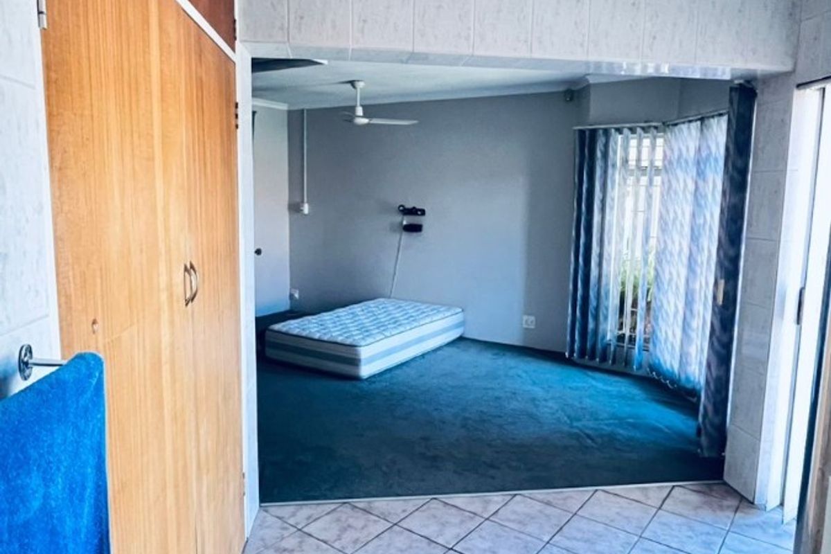 A bedroom area featuring built-in wooden cupboards, tiled flooring in the transition space, and carpeted flooring in the sleeping area.