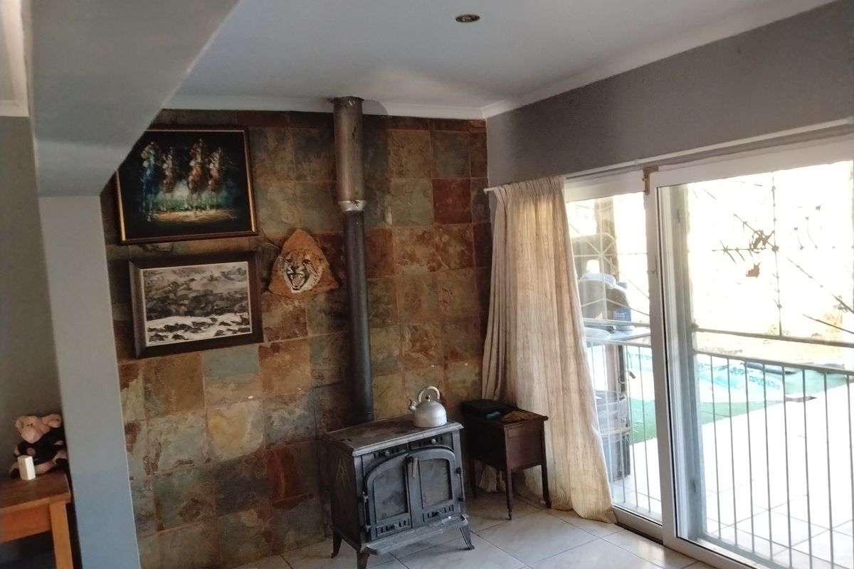Living area featuring a built-in stone feature wall with a cast iron fireplace and sliding glass doors leading to an outdoor patio.