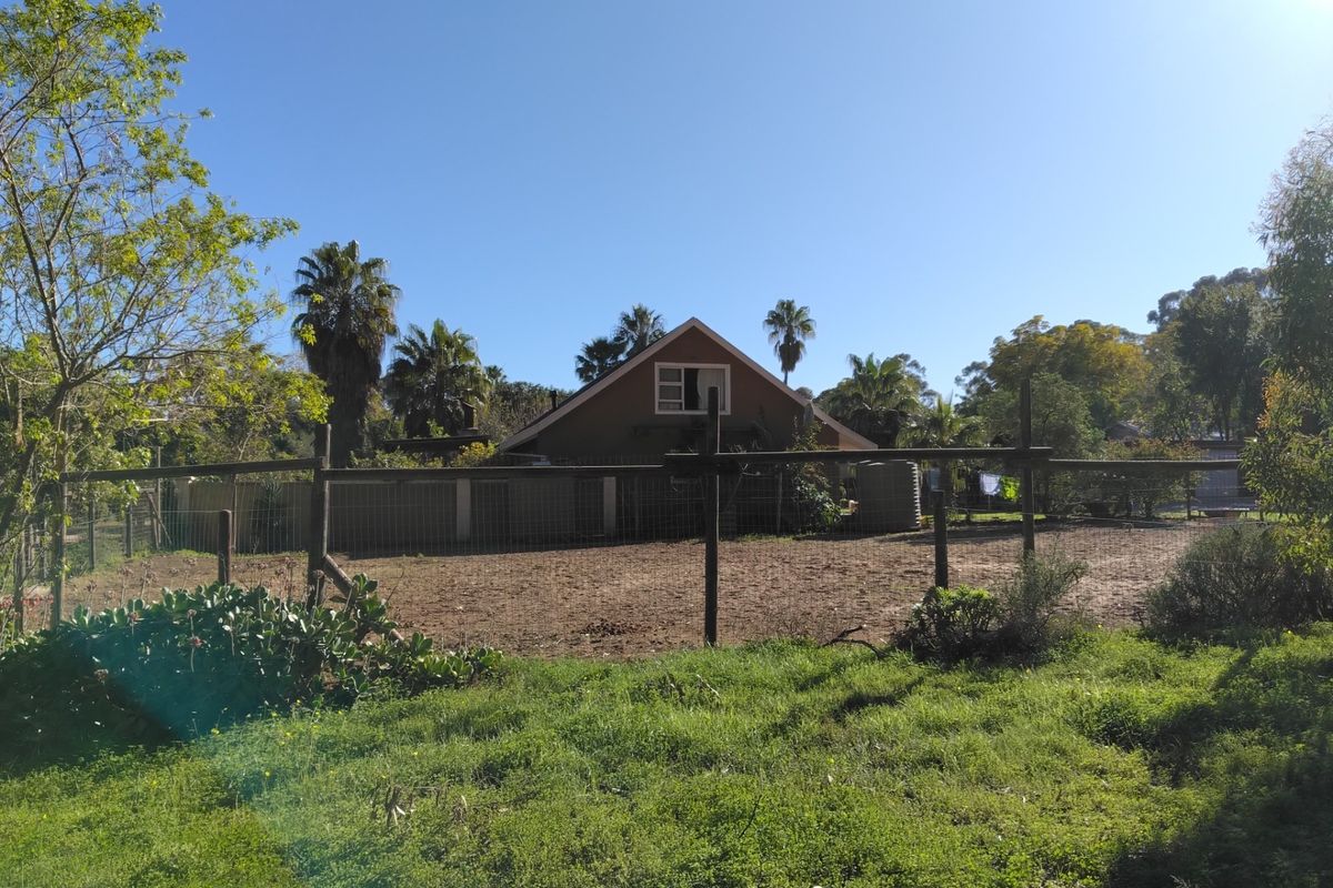 A view of the rear exterior of the property, featuring a large fenced yard area and established garden surroundings.