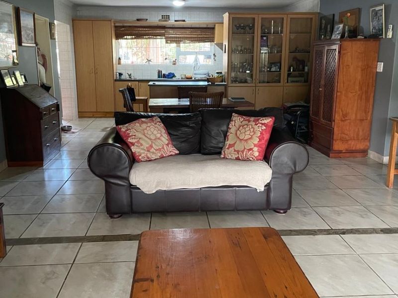 Open-plan living and kitchen area featuring tiled flooring, built-in wooden cabinetry, and a functional layout connecting the kitchen to the main living space.