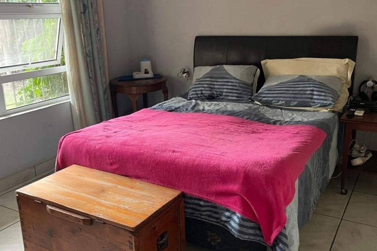 A functional bedroom featuring tiled flooring and a large window, providing a neutral space ready for personal updates.