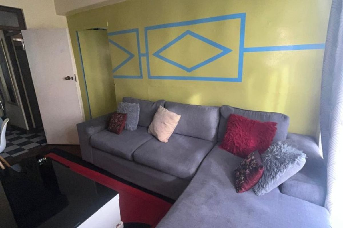 A living room area featuring a painted accent wall with geometric detailing and a standard interior door leading to an adjacent space.
