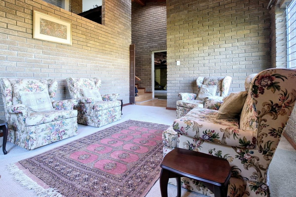 Spacious living area featuring high ceilings, exposed brick walls, and a mezzanine level, creating an open and architectural atmosphere.