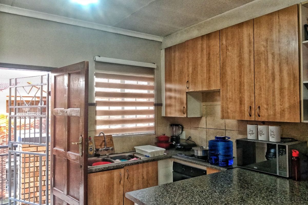 Functional kitchen featuring wood-look cabinetry, granite countertops, a double sink, and a built-in stove, with direct access to an exterior area.