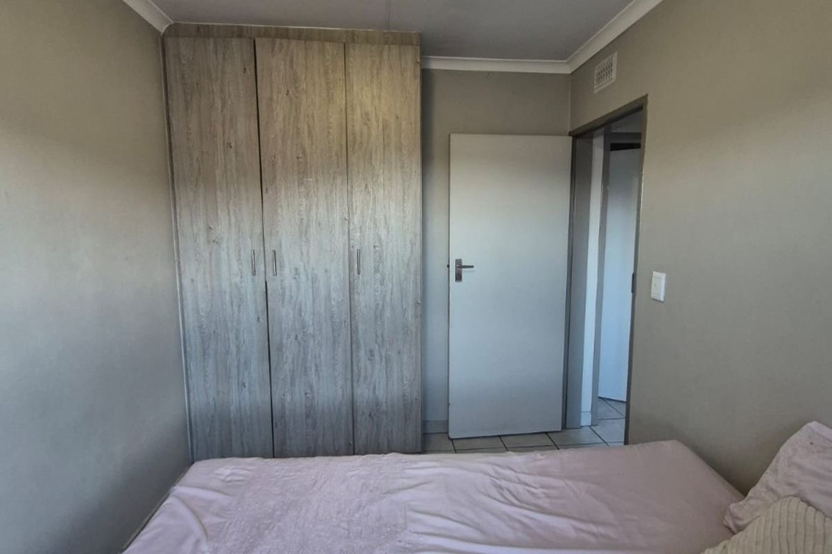 A bedroom featuring built-in wooden cupboards and a ceiling-mounted light fixture, providing functional storage and basic lighting.