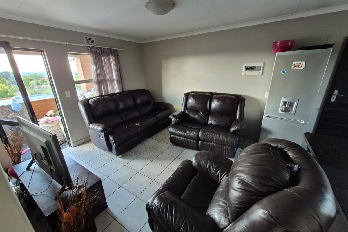 A living room area featuring tiled flooring, access to a balcony, and a neutral wall finish.
