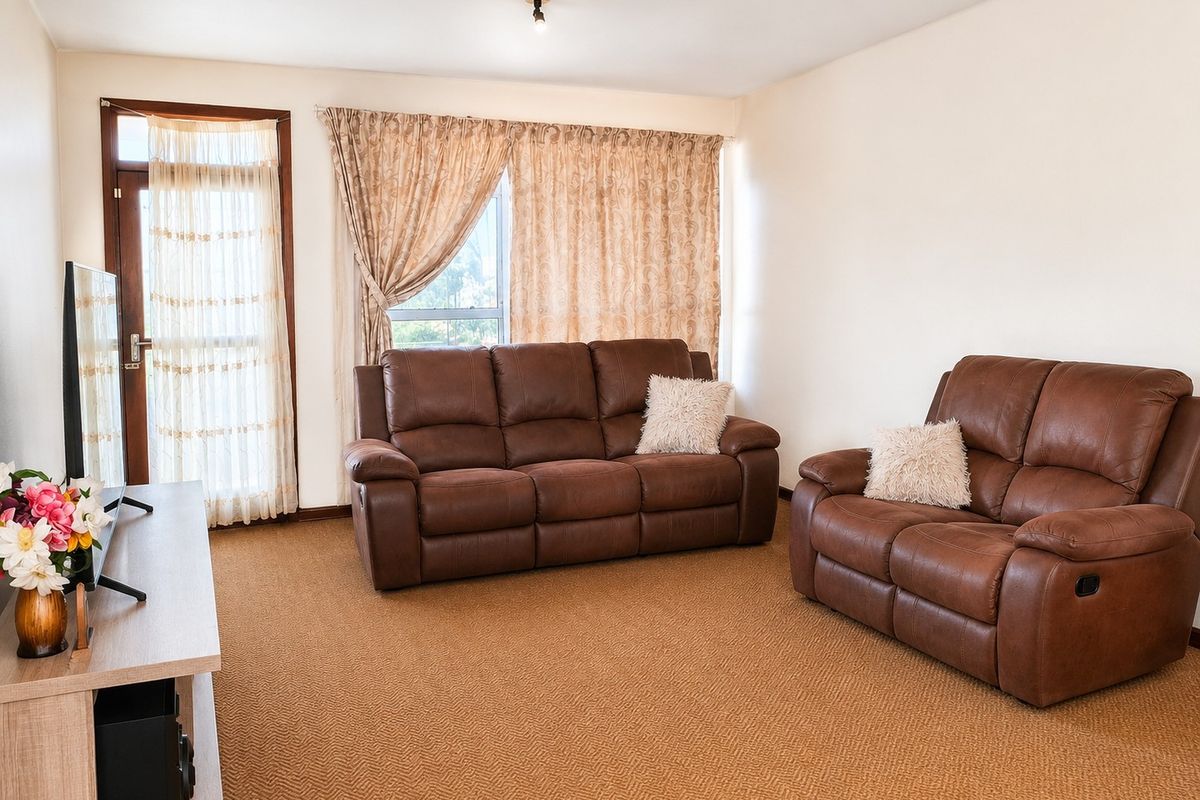 A living room featuring carpeted flooring, a glass door leading to an outdoor area, and a window with curtains.