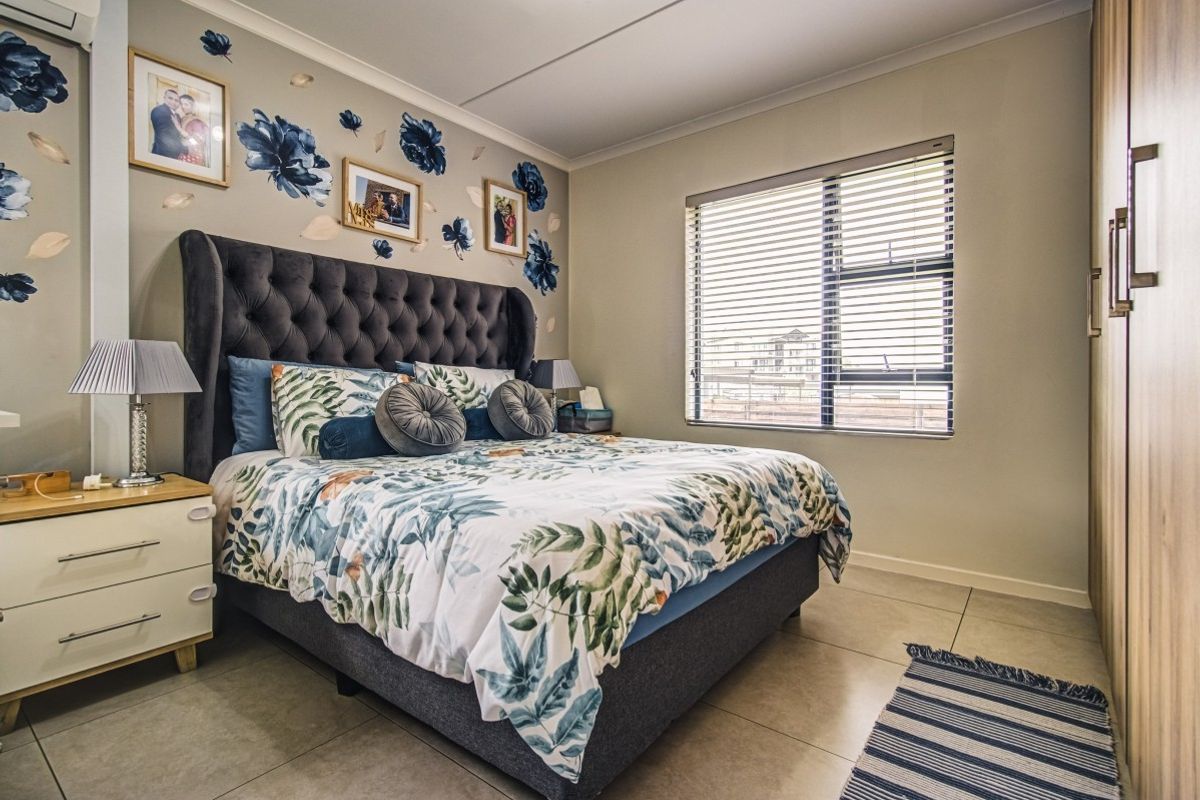 A well-maintained bedroom featuring tiled flooring, built-in cupboards, and a window with fitted blinds.